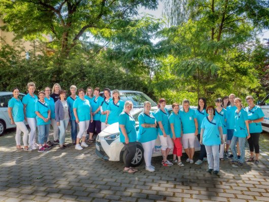 Das gesamte Team des ambulanten Pflegedienstes Bautzen der Diakonie Sozialstation steht vor den Dienstfahrzeugen.