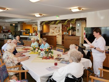 Bewohnerinnen und Bewohner sitzen gemeinsam am Tisch und spielen Bingo